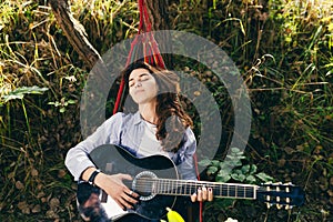 Beautiful woman resting on a hammock with guitar