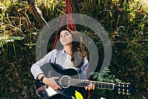 Beautiful woman resting on a hammock with guitar