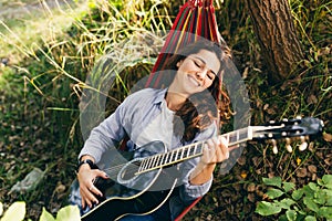 Beautiful woman resting on a hammock with guitar