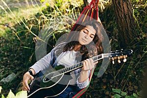 Beautiful woman resting on a hammock with guitar