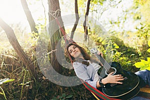 Beautiful woman resting on a hammock with guitar