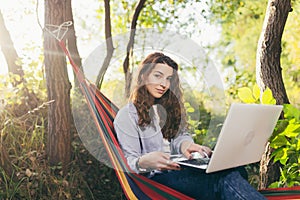 Beautiful woman resting on a hammock with laptop