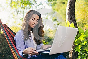 Beautiful woman resting on a hammock with laptop