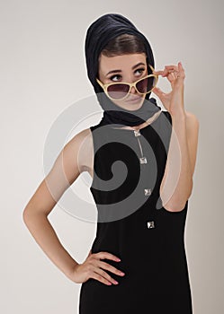 Beautiful woman in retro style with headscarf and sunglasses on light background