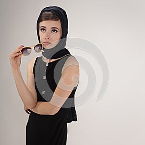 Beautiful woman in retro style with headscarf and sunglasses on light background photo