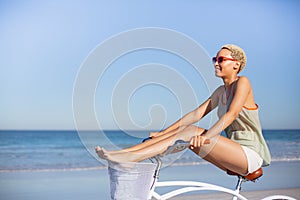 Beautiful woman riding bicycle with her legs on handlebars at beach