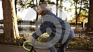 Beautiful woman riding bike on city paved road. Woman bicycle rider have a ride in the morning in the park. Lens flares