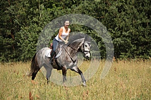 Beautiful woman riding gray horse in the forest