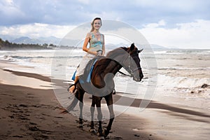 Beautiful woman riding horse on the beach. Outdoor activities. Caucasian woman wearing skirt. Traveling concept. Cloudy sky. Sea