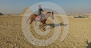 Beautiful woman riding horse at Giza pyramids complex