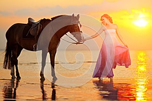 Beautiful woman riding a horse at sunset on the beach. Young girl with a horse in the rays of the sun by the sea.