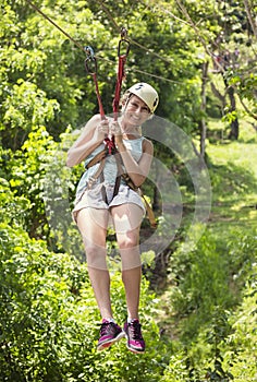 Beautiful woman riding a zip line in a lush tropical forest