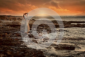 Beautiful woman  in rocks seashore at sunrise