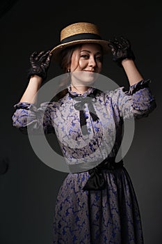 A beautiful woman in a romantic dress of the 19th century. Retro style, with a straw hat and lace gloves. Historical