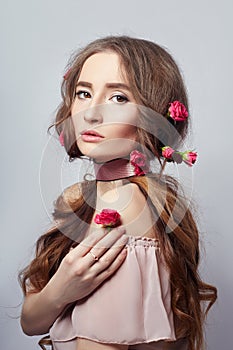 Beautiful woman with rose flowers in her long hair, a bandage around her neck. Clean beautiful face skin, hair care cosmetics.