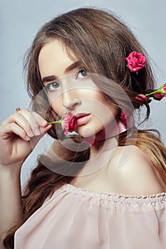 Beautiful woman with rose flowers in her long hair, a bandage around her neck. Clean beautiful face skin, hair care cosmetics.