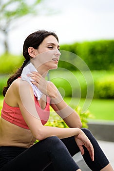 Beautiful woman runner has used a white towel wipe her face after running in the garden