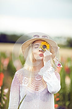 Beautiful woman in a rural field scene outdoors, with sunflower and sunhat