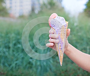 Beautiful woman's hand holding a colorful ice-cream cone. Close up. Outdoor. Summer time