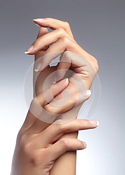 Beautiful woman`s hands on light background. Care about hand. Tender palm. Natural manicure, clean skin. French nails