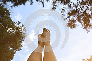 Beautiful woman`s legs on the sky background. Natural ecological photo. Perfect travel and girl`s rest day outdoors. Pine trees