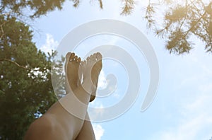 Beautiful woman`s legs on the sky background. Natural ecological photo. Perfect travel and girl`s rest day outdoors. Pine trees