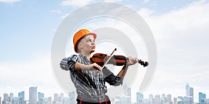 Beautiful woman in safety helmet playing violin