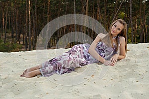 Beautiful woman on sand near woods of pine