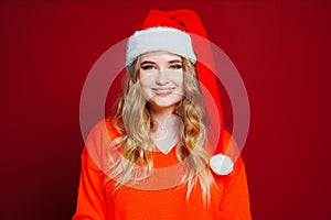 a beautiful woman in a Santa Claus hat on a red background.