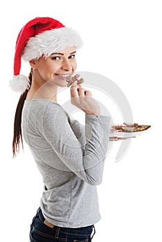 Beautiful woman in santa hat eating a cookie.