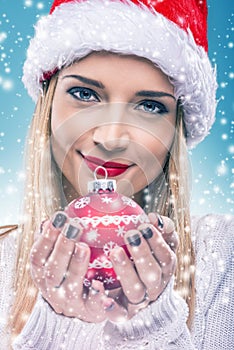 ÃÂ  Beautiful woman with santa hat holding red Christmas Ornament -close-up