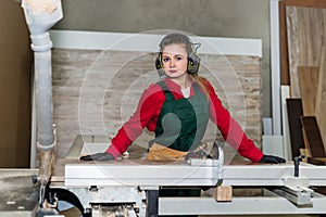 Beautiful woman sawing wooden plank in carpentry