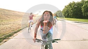 Beautiful woman sending kisses while cycling with friends, graded