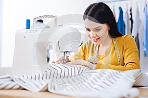 Beautiful woman sewing with a help of professional equipment