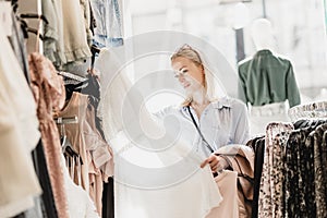 Beautiful woman shopping fashionable clothes in clothing store.