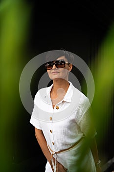 Beautiful woman with short brunette hair in white clothes and sunglasses. Fashion street photography. Fashion model
