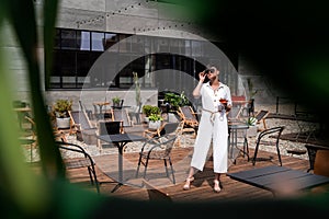 Beautiful woman with short brunette hair in white clothes and sunglasses. Fashion street photography. Fashion model