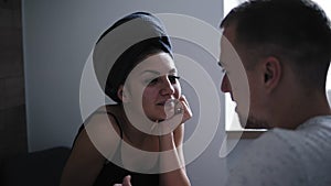 Beautiful woman after shower with dark towel on her head having conversation talking to her boyfriend in front. Young