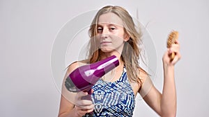 Beautiful woman after shower is drying hair with hairdryer