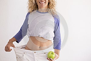 Beautiful woman showing her old big pantalon after losing weight ah home - fitness at home and working to stay better with photo