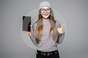 Beautiful woman showing a smart phone with thumb up isolated on grey background