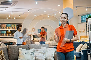 beautiful woman shows thumb holding a tablet standing in furniture store