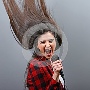 Beautiful woman singing with the microphone against gray background