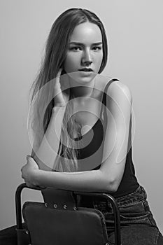 Beautiful woman sit on chair and touching her long hair.