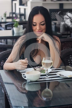 Beautiful woman sits in a cafe and eats cake