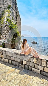 Beautiful woman sits on the rock at the sea