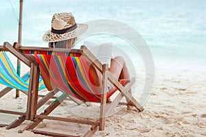 Beautiful woman sitting on beach reading a book