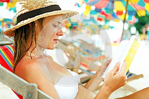 Beautiful woman sitting on beach reading a book