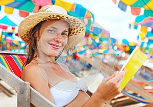 Beautiful woman sitting on beach reading a book