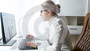 Beautiful young woman sitting behind desk and using computer